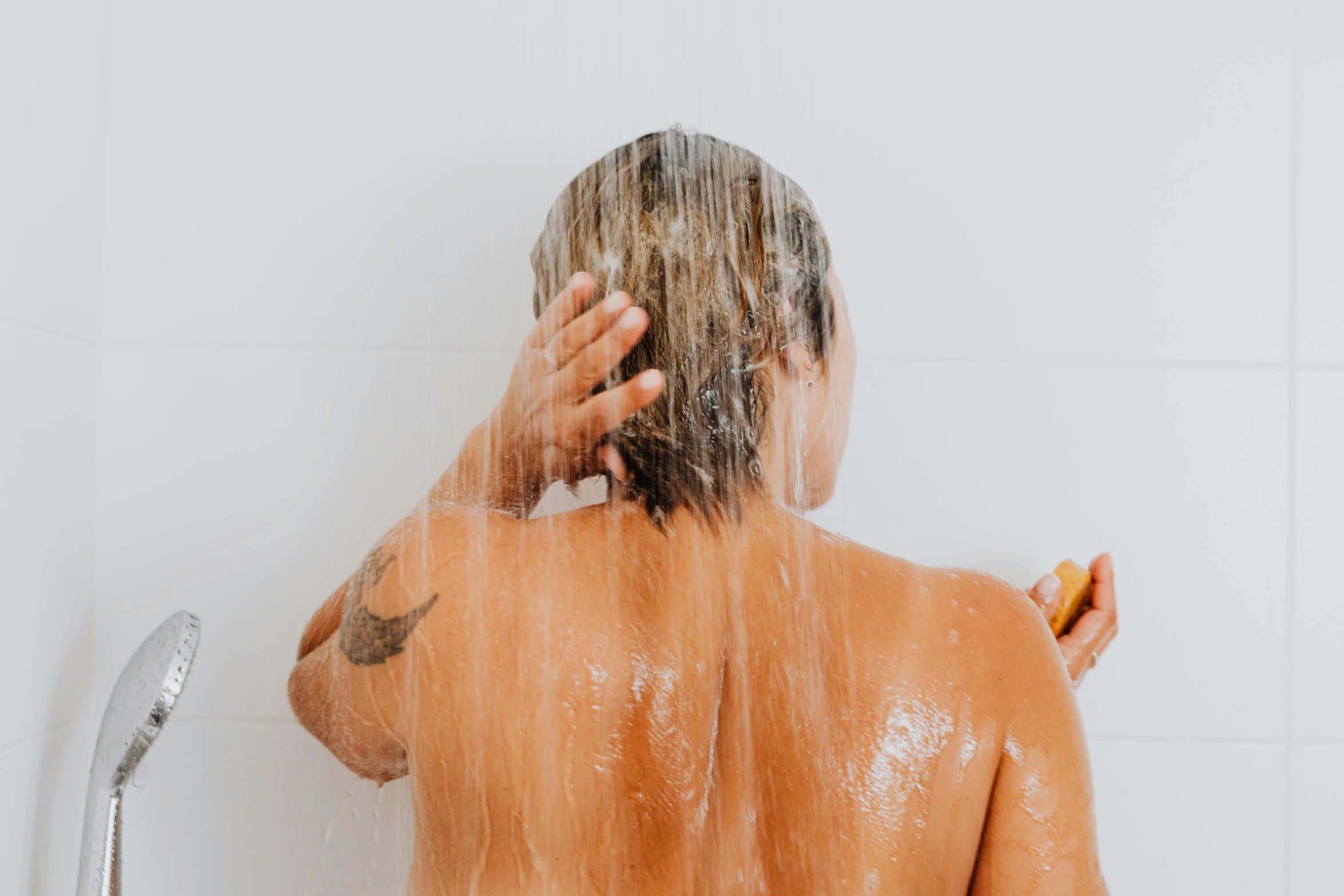 a woman standing in the shower with some hair flying from her head