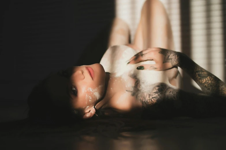 a person with tattoos laying on a wooden floor