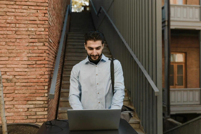 a man using his laptop at the top of some stairs