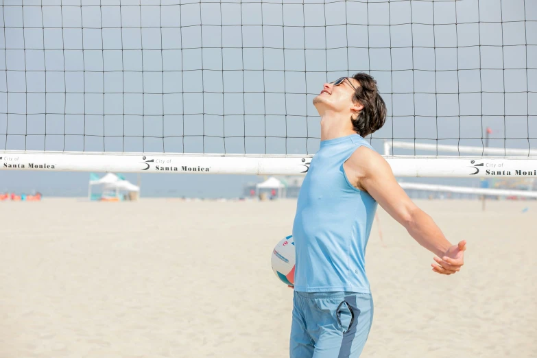 a man playing volleyball on the beach in front of a volleyball net