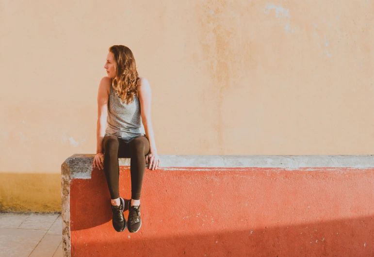 a woman sitting on the edge of a wall with her feet crossed