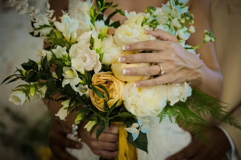 a bride holds a bouquet of flowers to the side