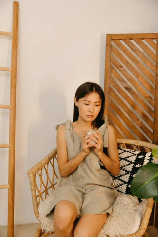 a woman sits on the wicker chair with her hands together, praying