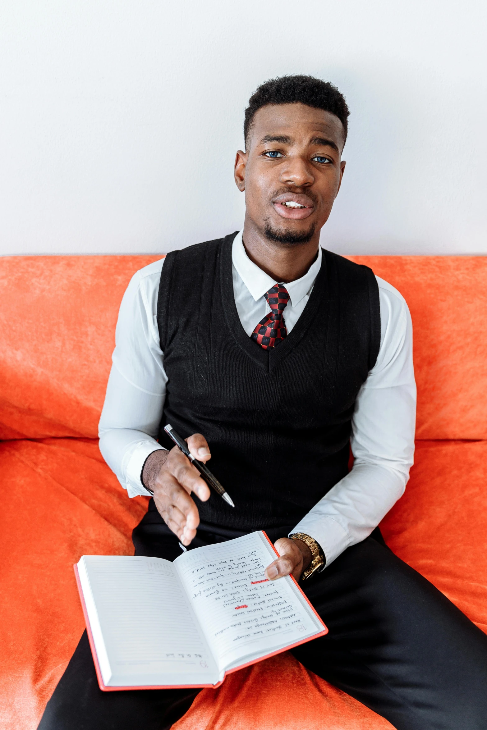 a man in a vest is holding a note book and pen