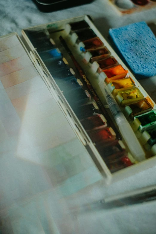 an open book and water colors on a table