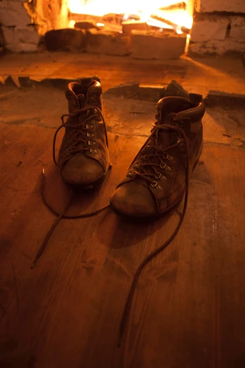 a pair of brown combat boots resting in front of a fire place