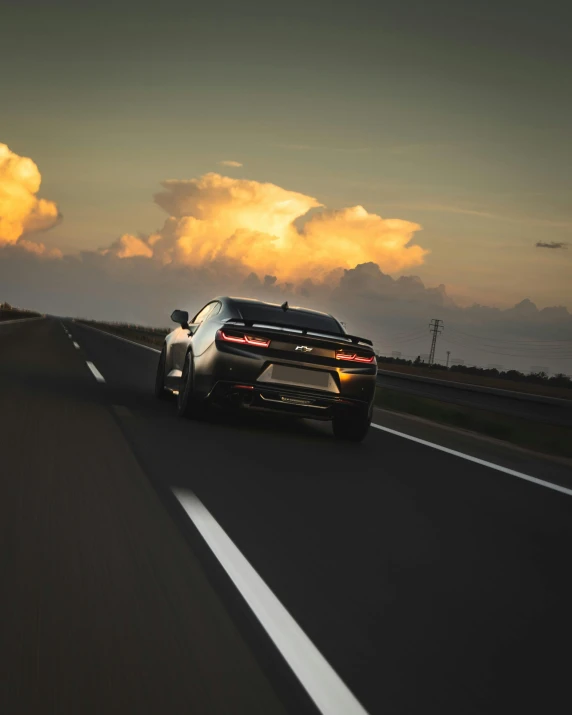 a supercar driving down the highway at sunset