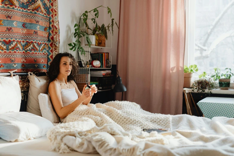 a beautiful young woman laying in bed under a blanket