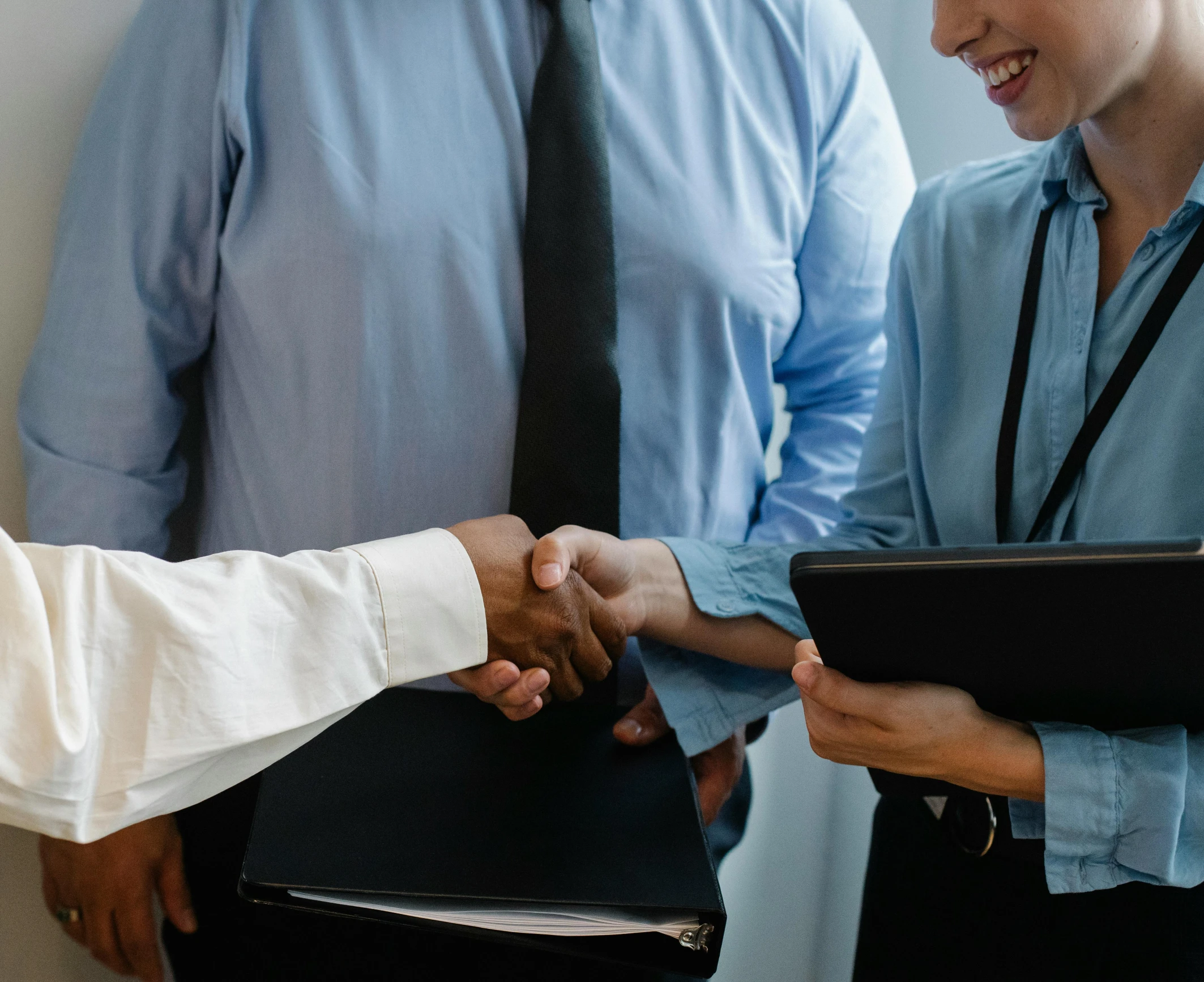 three people shaking hands with a man in a suit