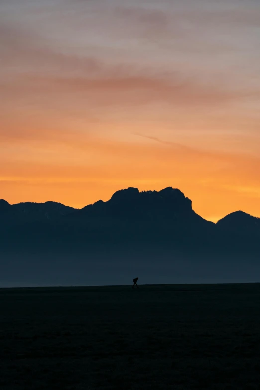 a silhouette of a person standing in an open field