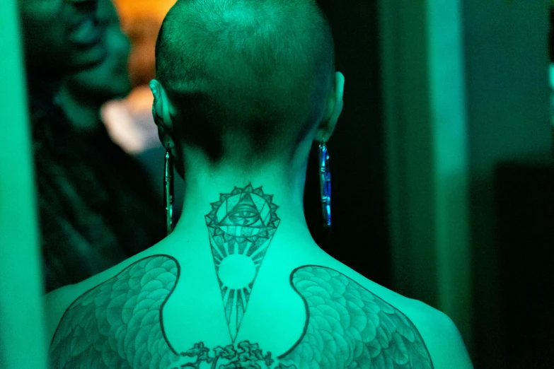 a tattooed man has his arm around his neck and behind his head