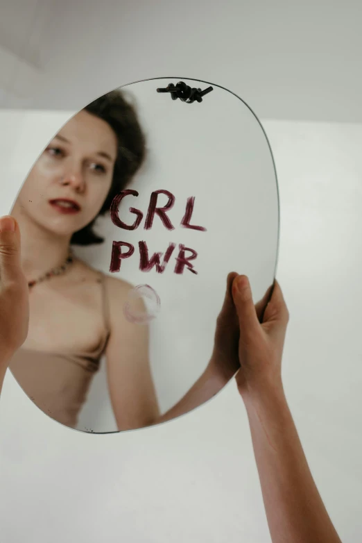 a woman holding a mirror with a word painted on it