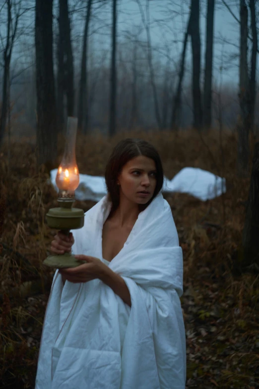 woman holding lantern on her shoulder in wooded area