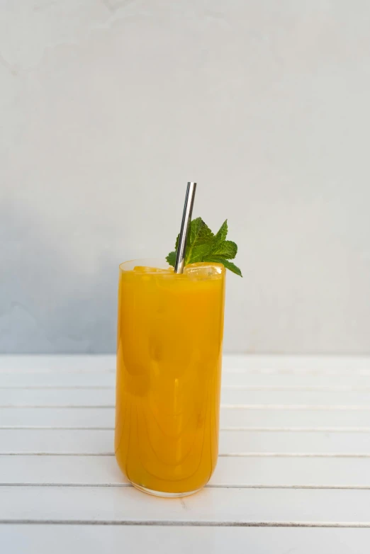 a drink with orange juice and a green leaf in it