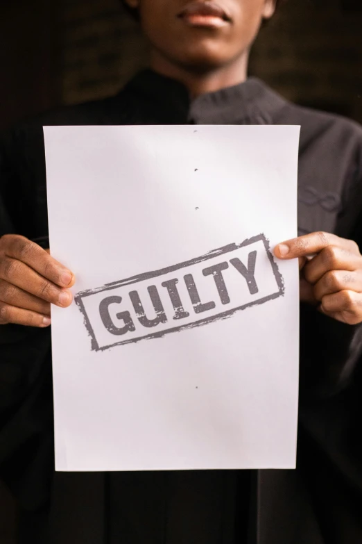 a person holding up a piece of paper that says guilt