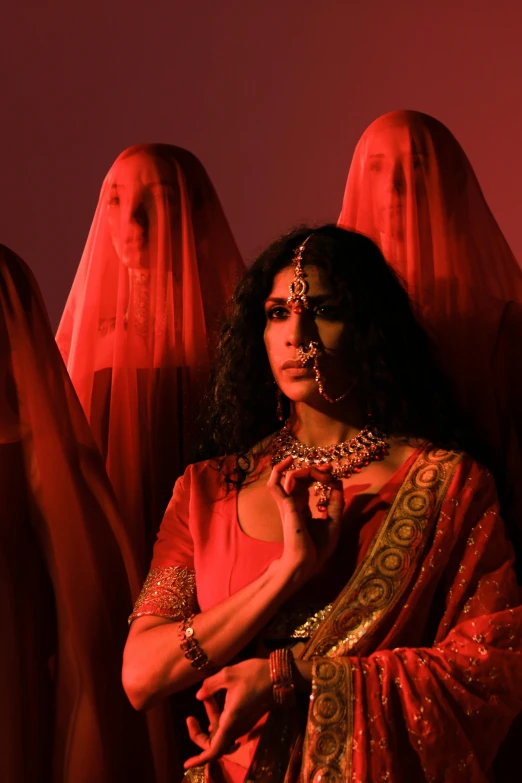 a woman wearing some bright jewelry stands in front of red ghost statues