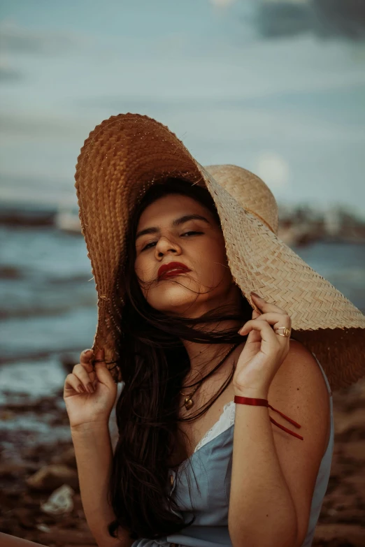 a woman wearing a sun hat while sitting on the beach