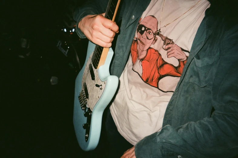 a man is playing the guitar that he has on his shirt