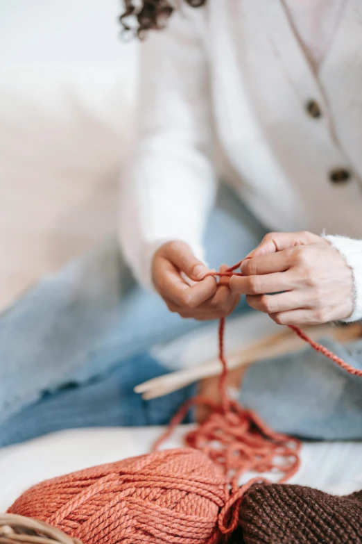 a woman knitting a pair of slippers with two yarn needles