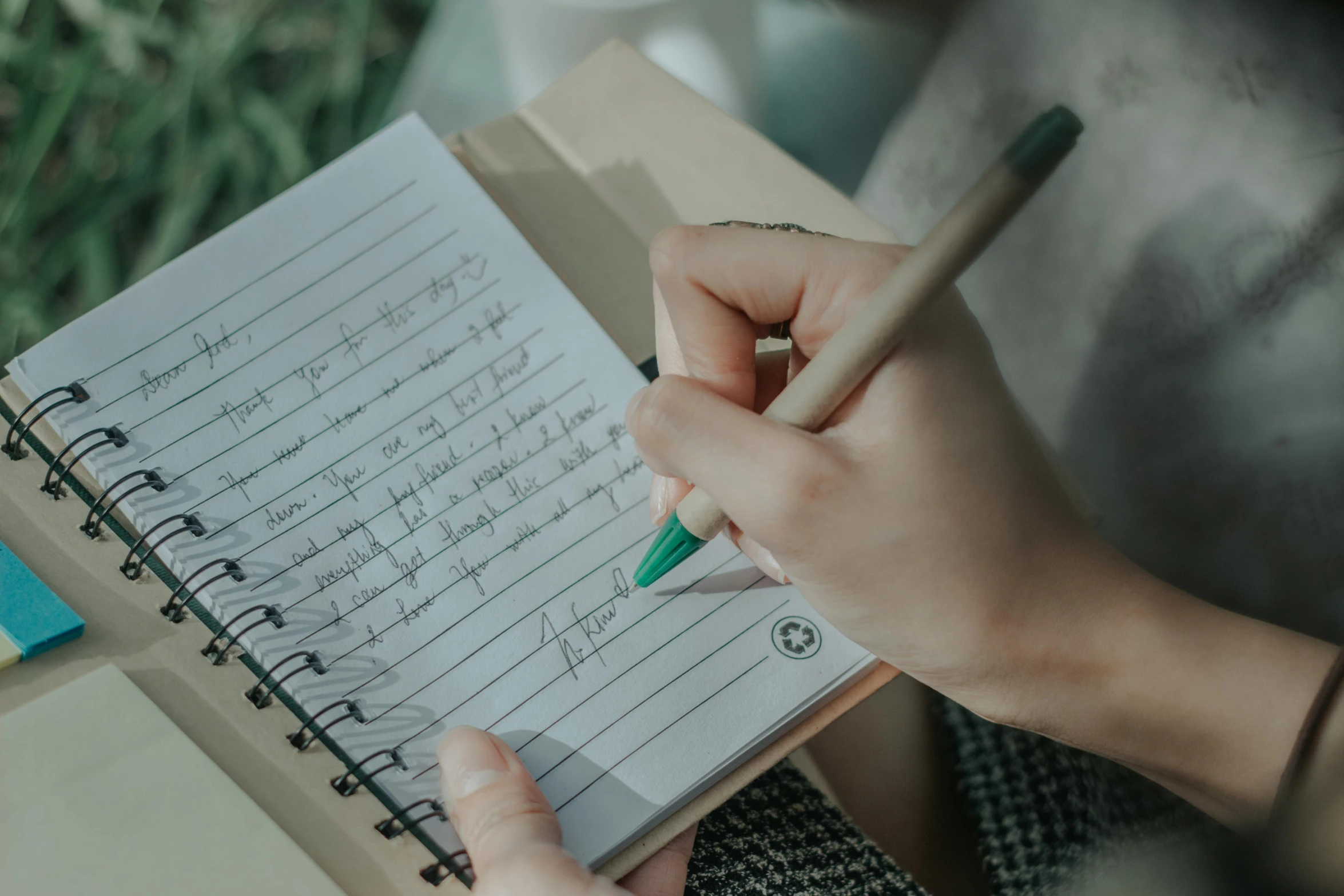 a hand with a pen and notebook sitting on a table