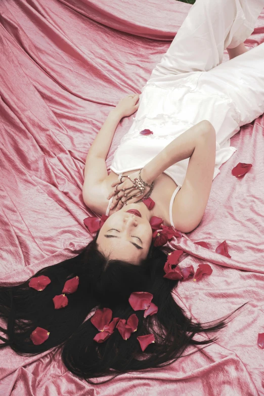 a woman laying on top of a bed covered in rose petals