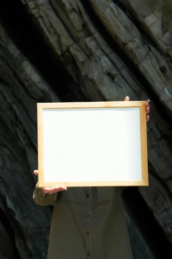 a person holding up a white paper picture frame