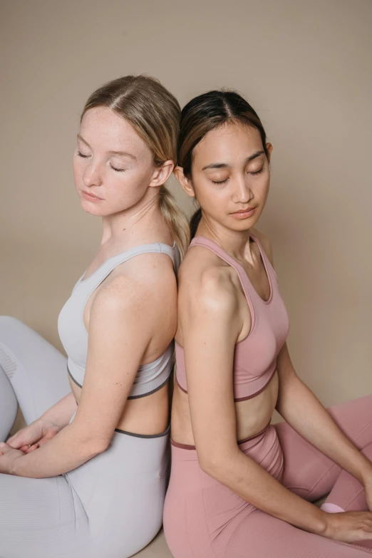 two women in matching outfits practicing yoga together