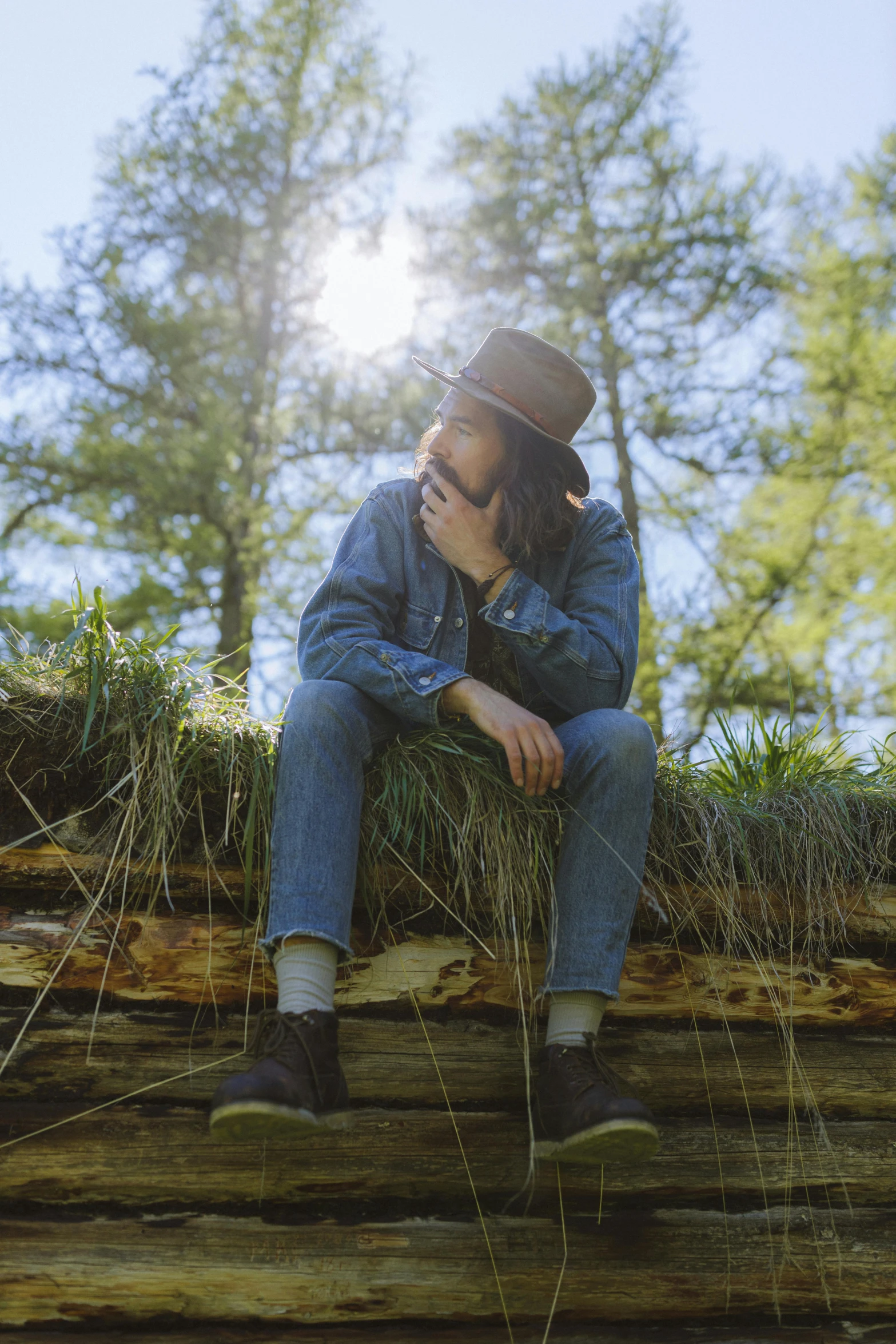 a man wearing a hat sitting on top of a log