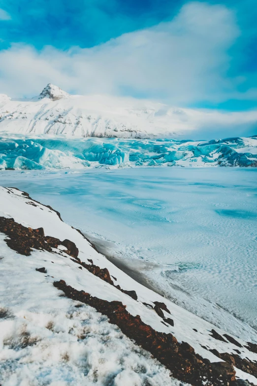 a landscape of ice covered water in front of a mountain