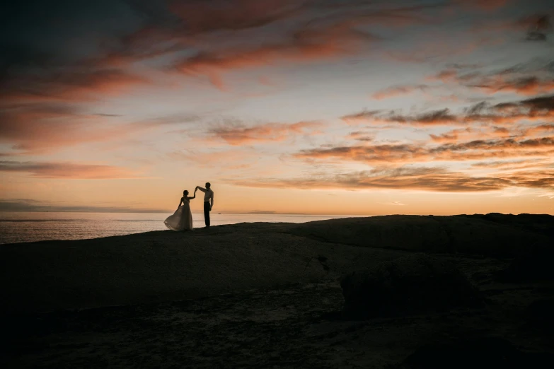 two people stand in front of the ocean on their wedding day