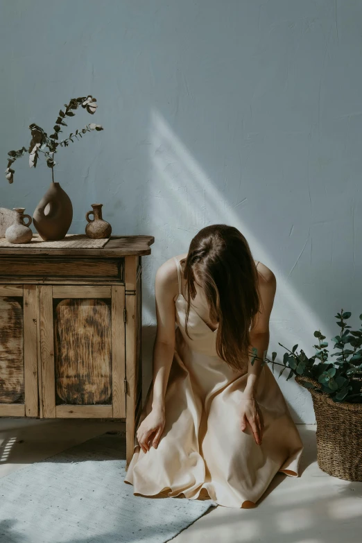 a woman sitting on a floor in front of a dresser