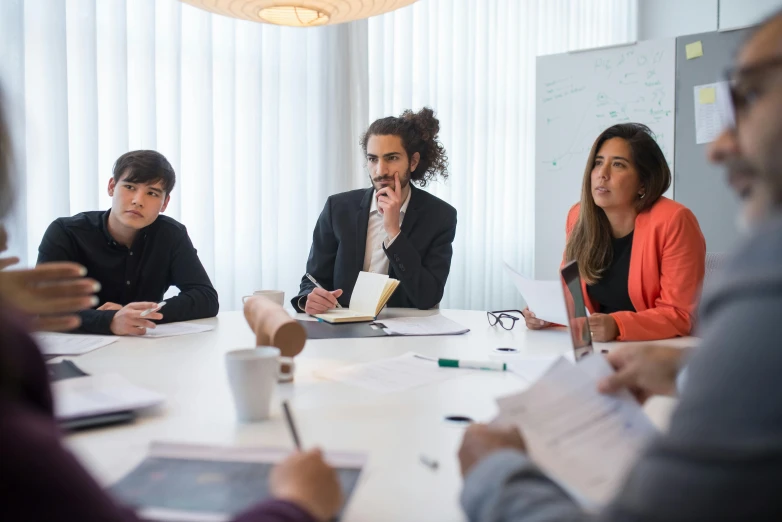 a group of business people sitting around a white table