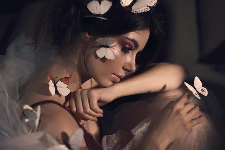 woman with white flowers and feathers resting her head on her hands