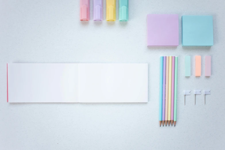 paper, pencils, eraser, pens, and other office supplies laid out on a white table