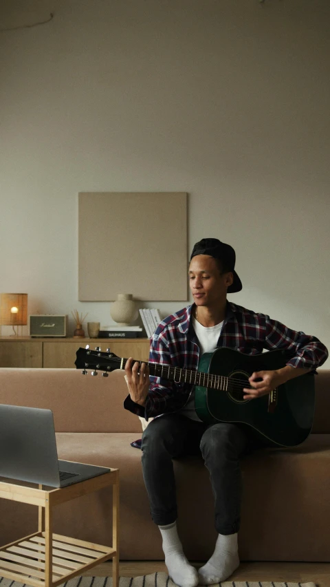 the man is playing an acoustic guitar on the couch