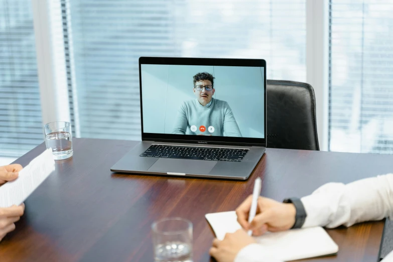 two men sitting at a conference table looking at a computer screen