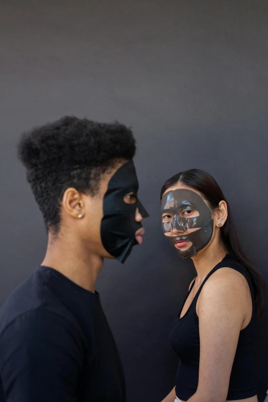 two people with faces painted in black standing