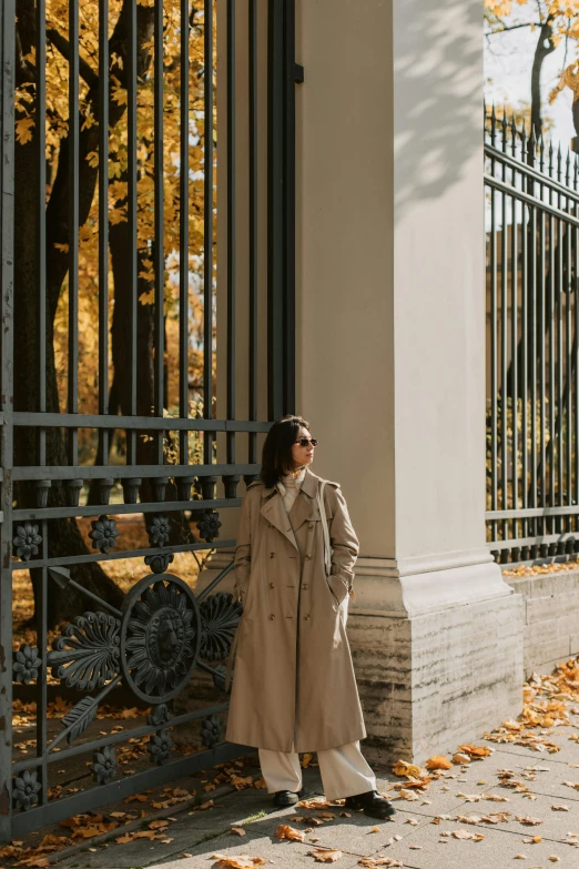 a young woman standing next to an iron gate
