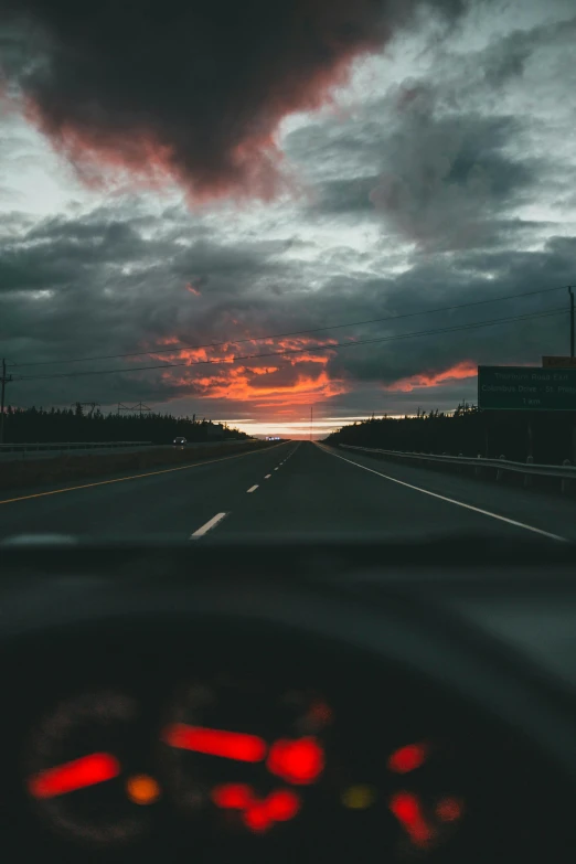 a view out of the inside of a car windshield as the sun sets