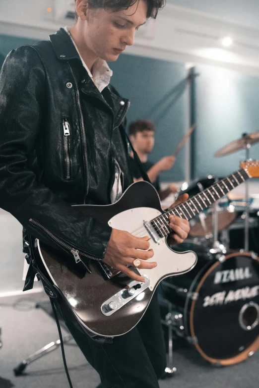 a man playing a guitar while another man plays drums behind him