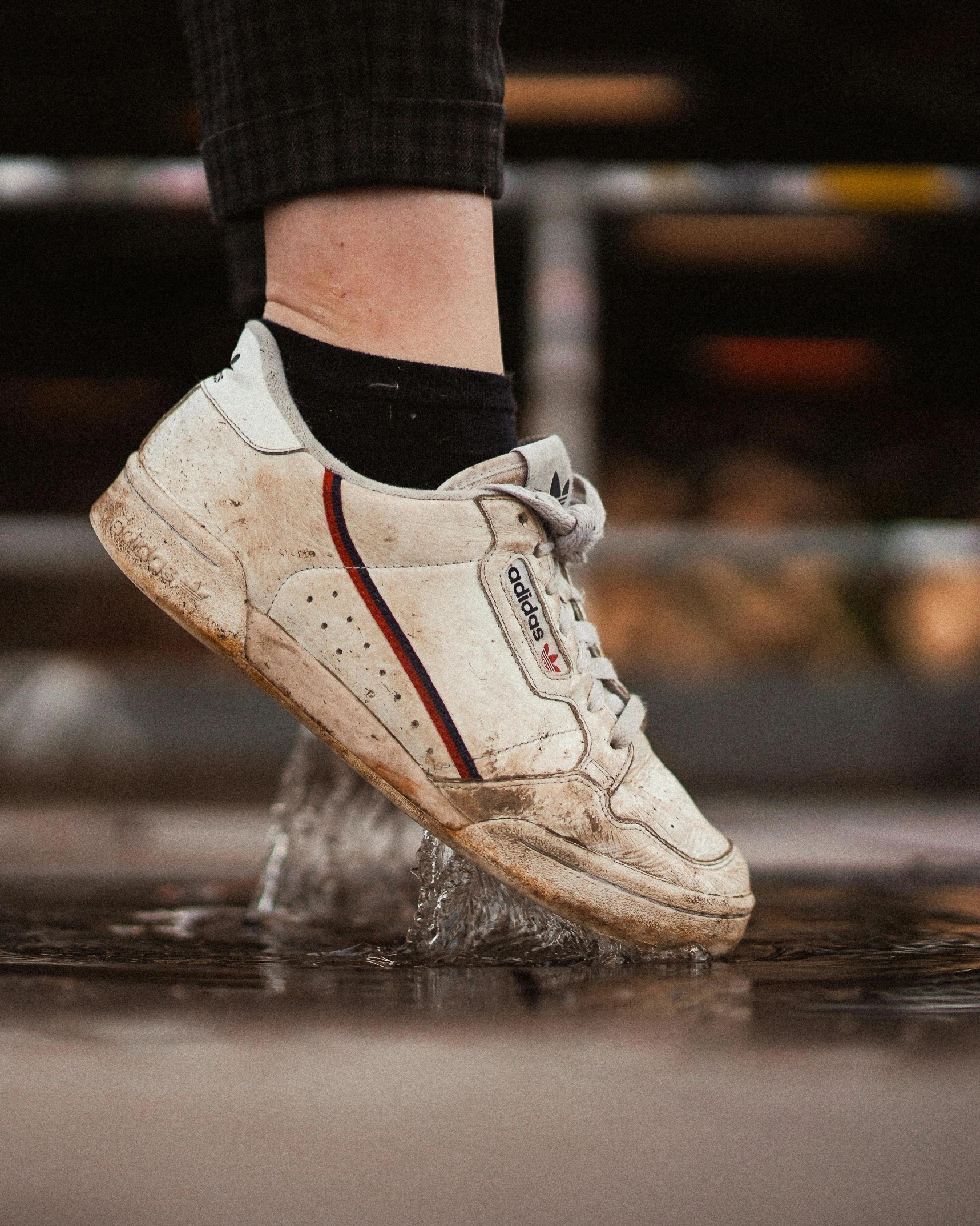 a white shoe with an orange stripe and black socks