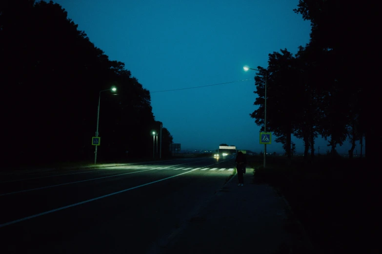 silhouette of a person standing near a street at night