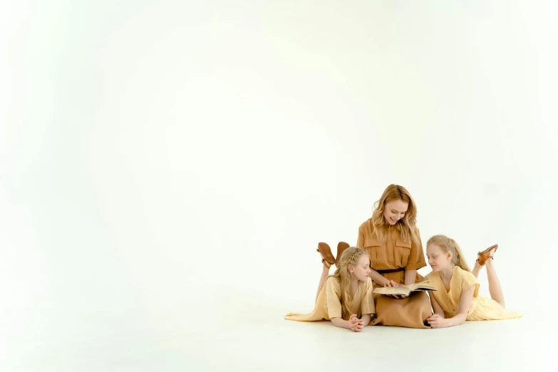 the woman reads the book while two other children look on