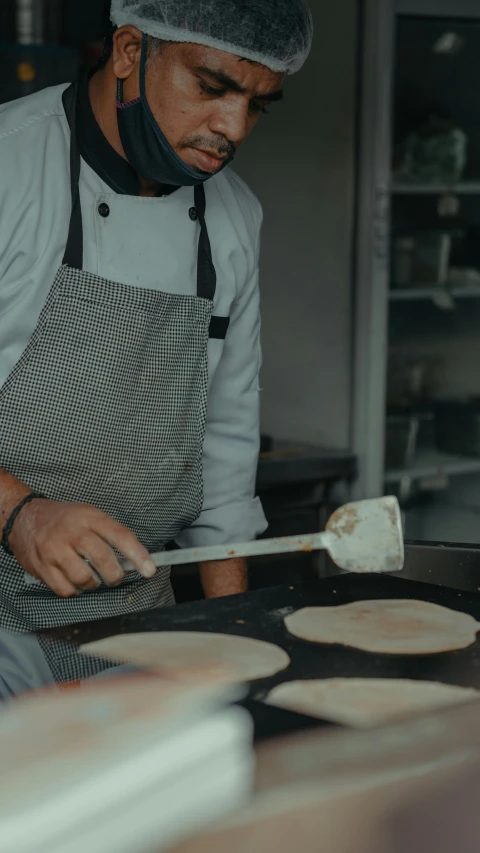 a baker is looking at a tray with several pans