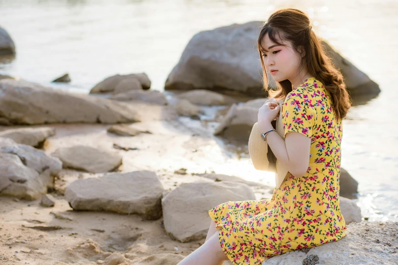 a girl sitting on a rock by the water