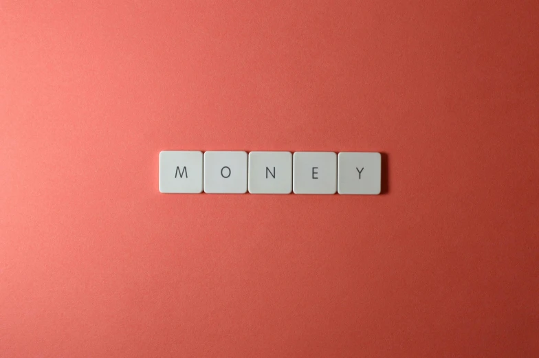 a piece of wood spelling money on red paper