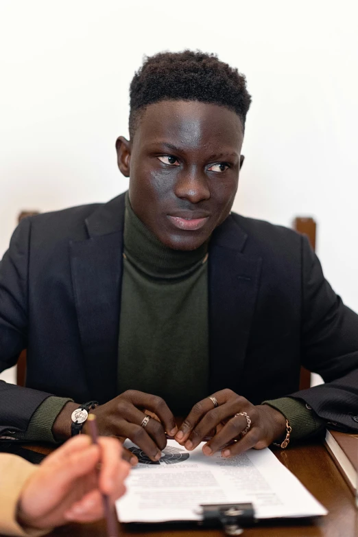 the young man has his finger in his hand while at a table