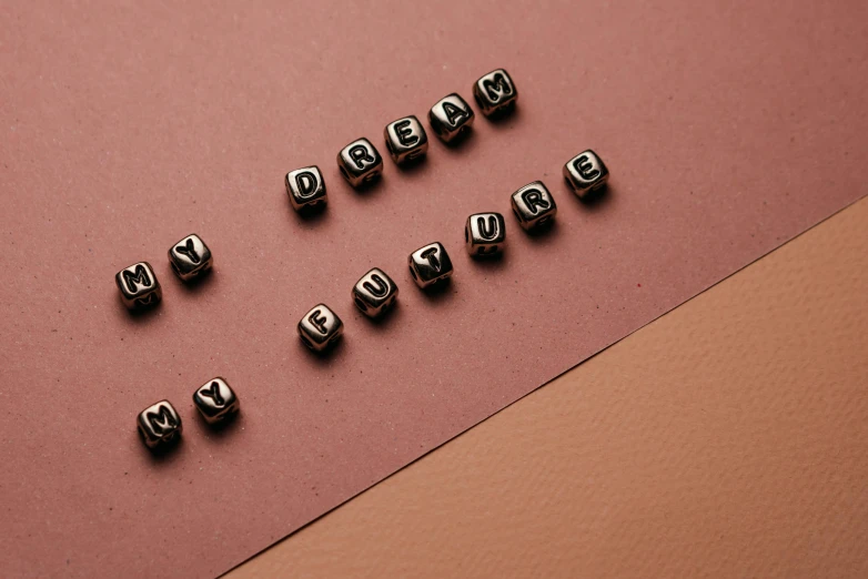 six silver metal beads next to a pink background