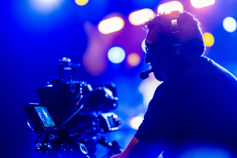 man on stage wearing headphones using a video camera