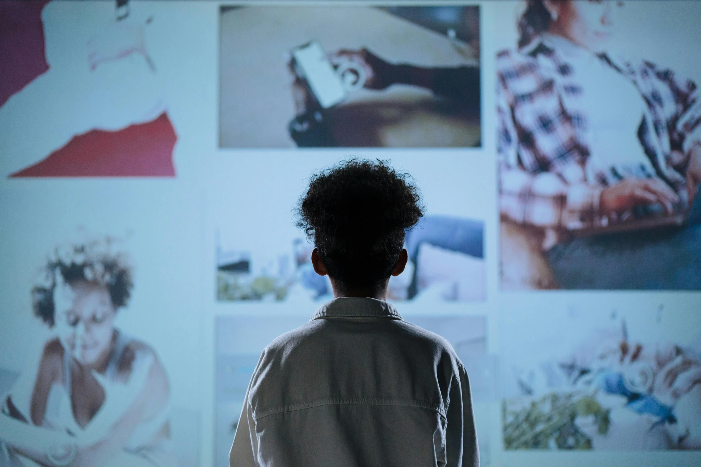 a man standing in front of a wall with pictures on it